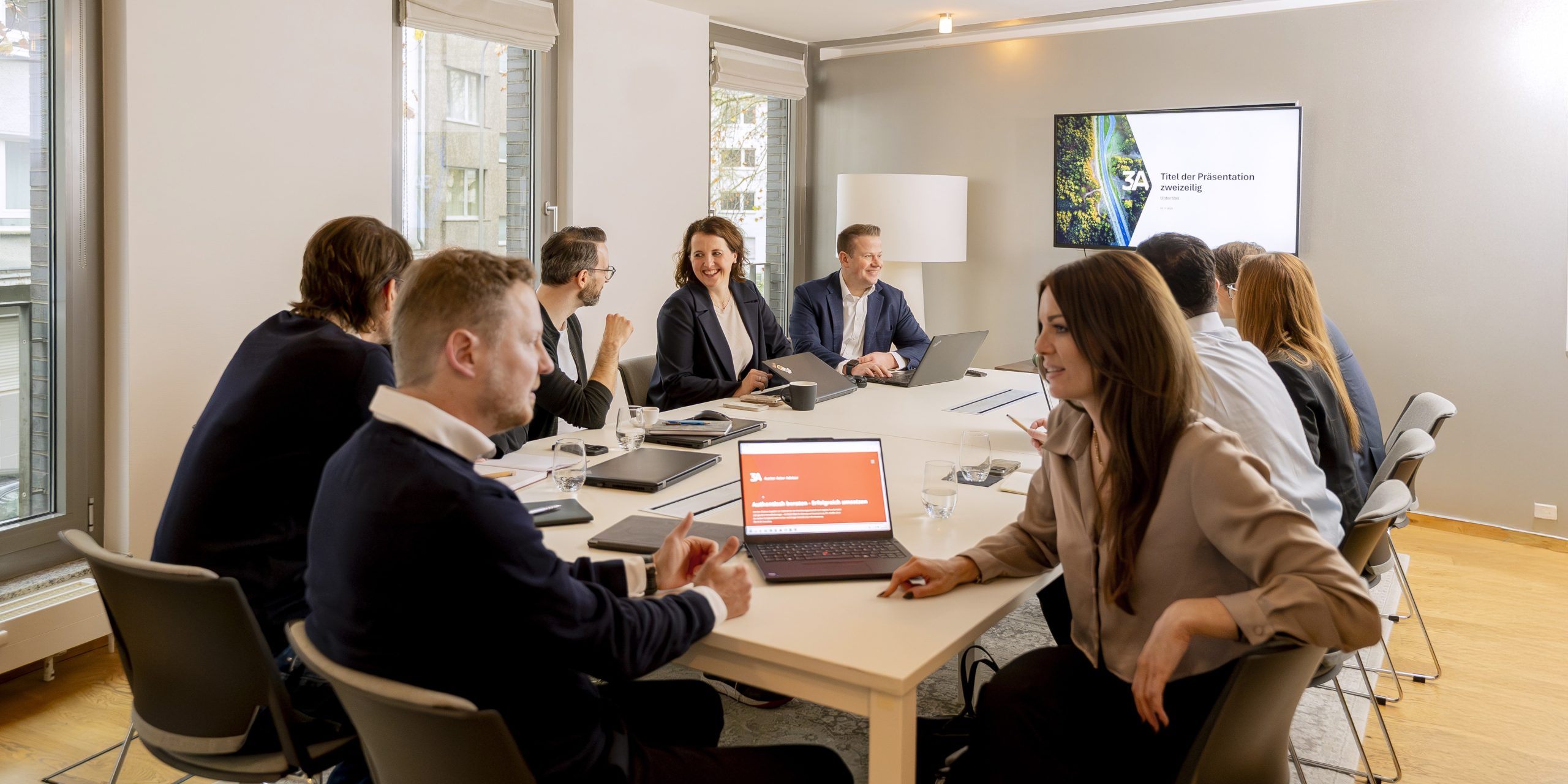Elf Mitarbeiter am Konferenztisch mit Beamer